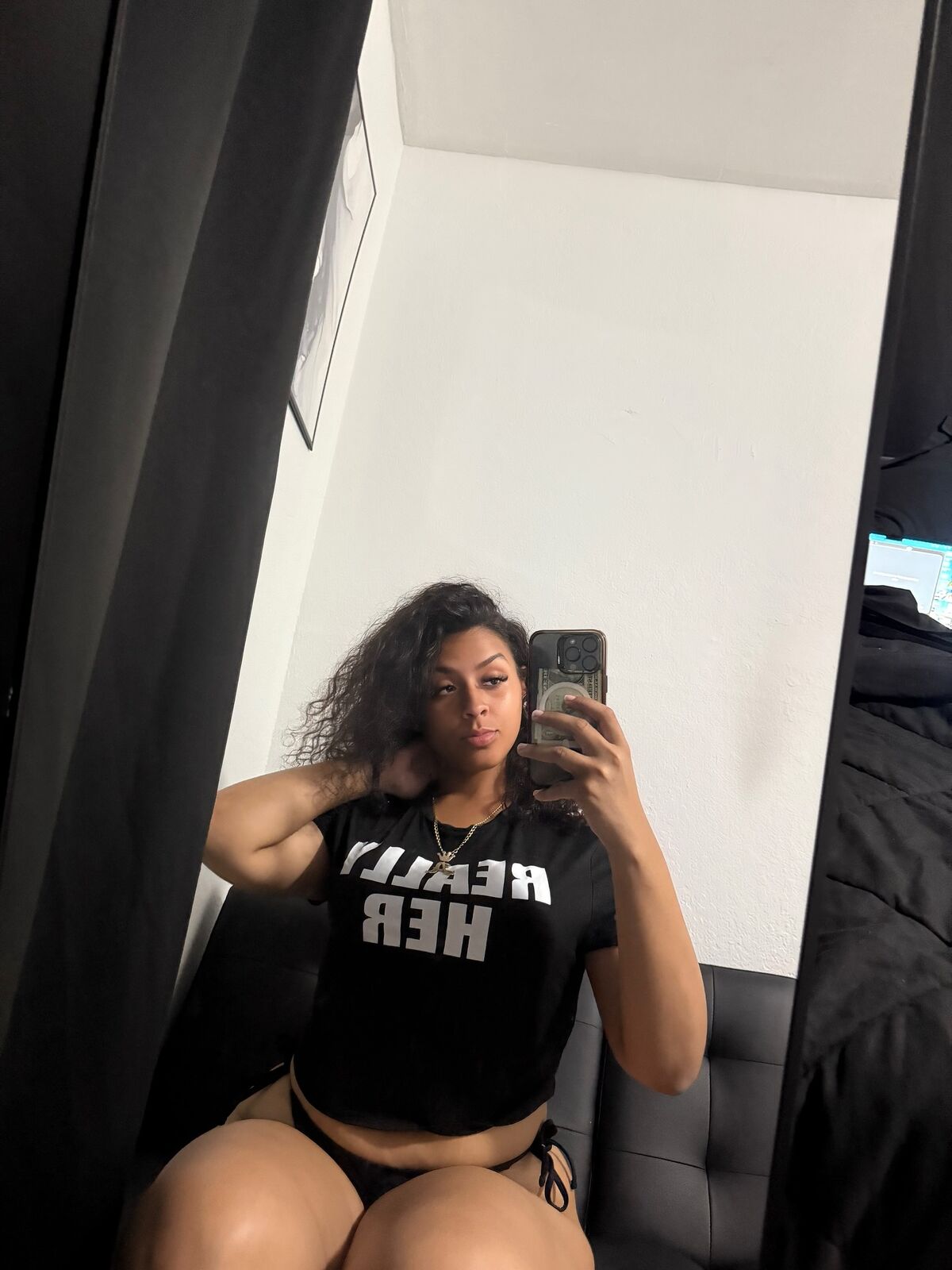 Mirror selfie of LA Real Ash wearing a black 'REALLY HER' t-shirt