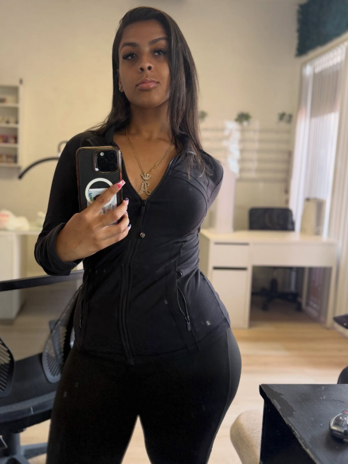 Mirror selfie of LA Real Ash in a black zip-up athletic jacket